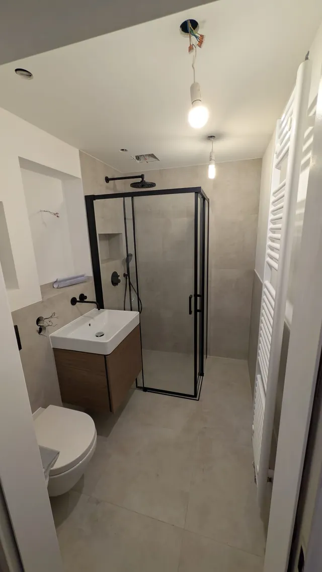 Badezimmer nach der Sanierung mit Duschkabine, WC und Waschtisch