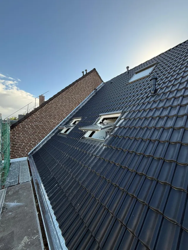 Neue Dachfenster in der fertigen Dachfläche mit anthrazitfarbenen Dachpfannen