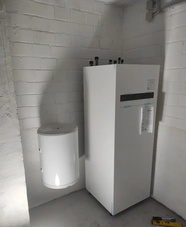 Wärmepumpen-Innengerät neben dem Warmwasserspeicher im Keller
